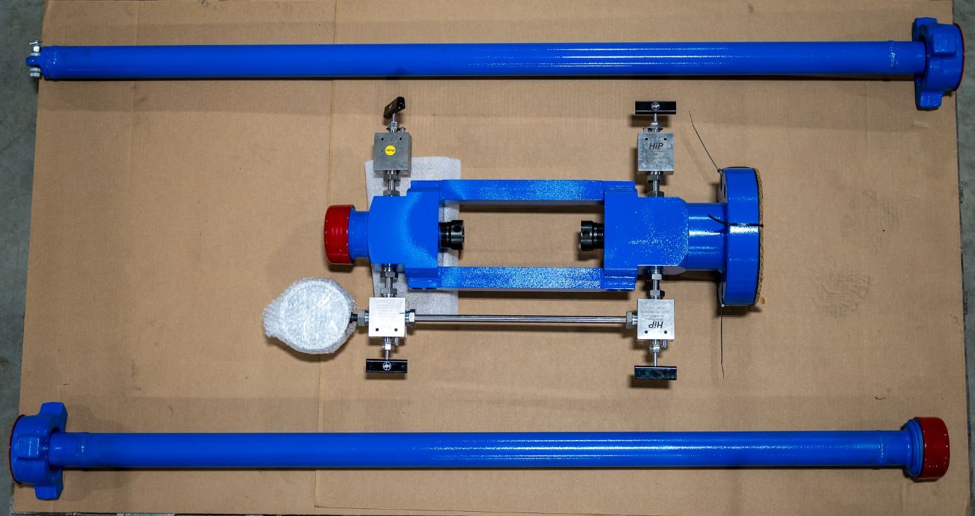 CAMTOP BPV lubricator with API flange end connection — blue body with flanged outlet, red thread protectors, polished rods and gauge manifold on workbench