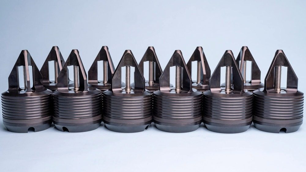 CAMTOP Type H back pressure valves production run — rows of black nitride BPV check valves with threaded tops arranged on workshop bench